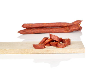 Wall Mural - Lot of whole lot of slices of piquant smoked sausage on wooden cutting board isolated on white background