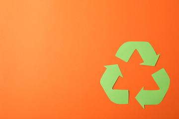 Recycling sign on orange background, top view