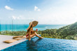 © Underwater girls - A beautiful girl in a red bathing suit is relaxing in a luxury villa by the pool with wine and in a hat taking cover from the sun. View of palm trees and the sea. Thailand, Koh Samui
