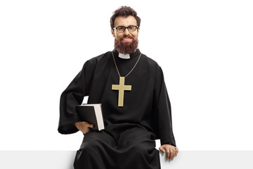 Christian priest sitting on a panel and holding a bible