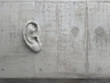 Cement sculpture in the shape of a human ear on a concrete wall. Illustration of the metaphor 