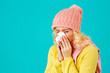 Cold and flu season- portrait of a woman in hat and scarf blowing her nose