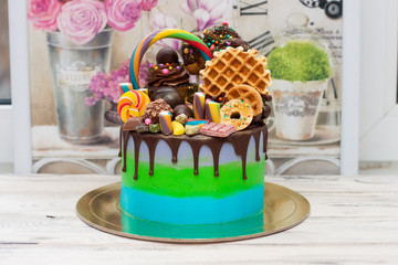 Wall Mural - Blue and green cake with dark chocolate, cupcake, lollipops, cake pops, ferrero, waffle, candies and sprinkles.