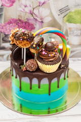 Wall Mural - Blue and green cake with dark chocolate, cupcake, lollipops, cake pops, ferrero, waffle, candies and sprinkles.