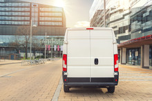 Small Cargo Delivery Van Driving In European City Central District. Medium Lorry Minivan Courier Vehicle Deliver Package At Residential Office Building In Downtown Area. Commercial Shipping Logistics