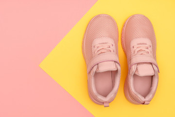 Pink sport shoes on colorful background. New sneakers on pink and yellow pastel background. Losing weight and sport concept. Top view, flat lay, copy space