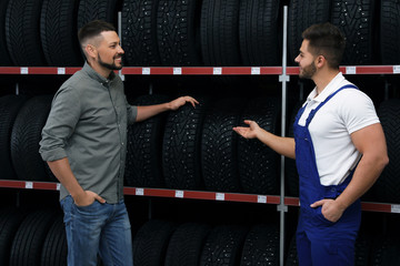 Poster - Mechanic helping client to choose car tire in auto store