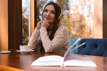 Canvas Print - Woman listening to audiobook at table in cafe