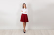 © hbrh - Full length of serious, confident young businesswoman with crossed arms, standing isolated against white wall. One single person. Business clothes, shirt, skirt. Copy space.