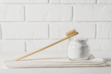 bamboo toothbrush with a white towel and powder for cleaning teeth in a bowl on a background of a li