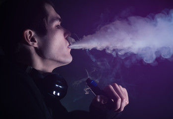 Wall Mural - man in the clouds of steam from electronic cigarette closeup. vaping man