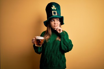 Sticker - Young beautiful woman wearing green hat drinking jar of beer on saint patricks day celebration serious face thinking about question, very confused idea