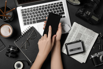 Wall Mural - Journalist with smartphone working at black table, top view