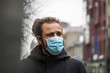 © Viesturs - Handsome young European man in winter clothes on the street with a medical face mask on. Closeup of a 35-year-old male in a respirator to protect against infection with influenza virus or coronavirus