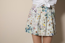 Young Woman Wearing Floral Print Skirt On Beige Background, Closeup