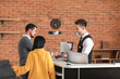 © Pixel-Shot - Couple paying for hotel room at reception