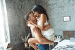 © Viktoriia - Mixed Race Couple. Young man holding woman in his arms in bedroom smiling before kiss passionate