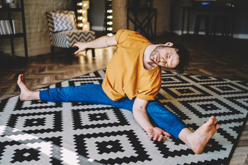Fototapete - Young bearded man training asana on floor