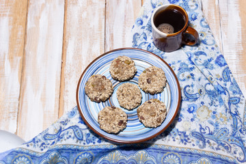 cup of coffee and vegan cookies on blue cover on wooden background