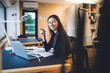 © BullRun - Portrait of successful hipster girl in optical glasses for vision protection smiling at camera during time for e learning on laptop computer, happy female freelancer doing distance job in coworking
