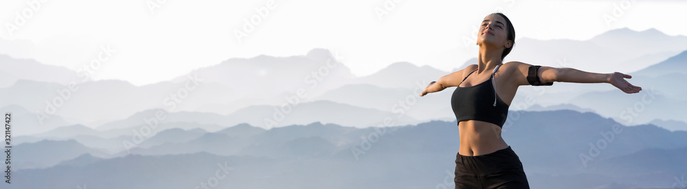 A thin athletic girl takes a break between classes on the background of mountains in the early morning, enjoys silence and freedom. - obrazy, fototapety, plakaty 