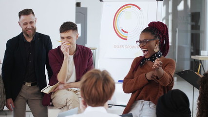 Healthy workplace, happy smiling young African boss business woman giving directions to diverse office employees.