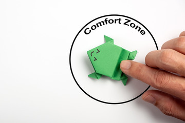 Wall Mural - Step out from the comfort zone concept. A dark green origami frog is ready to jump out of the comfort zone.