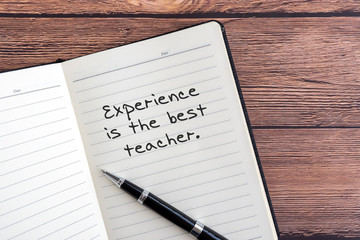 Wall Mural - Inspirational quotes - Experience is the best teacher. Notepad wooden background.