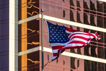 USA Flag. American flag. Flag of the United States flies waving beautifully in the strong wind. Background glass facade of modern office building