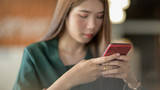 Fototapeta  - Close up view of female texting on smartphone in blurred simple office room background