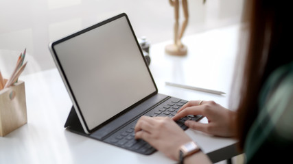 Sticker - close up view of female designer typing on blank screen tablet in simple co working space