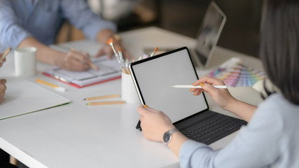 Cropped shot of female app developer drawing on mock up tablet in meeting room