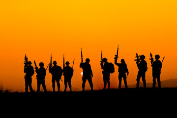 Wall Mural - silhouette of Soldier team backdrop of sunset sky.Soldier with machine gun patrolling 