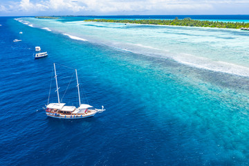 Beautiful turquoise ocean water with boats on it top view aerial photo. Maldives island and sea, amazing aerial photo. Wonderful landscape scenery, exotic travel landscape, summer vacation, holiday