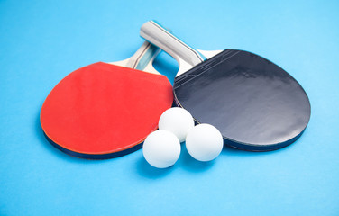 Table tennis rackets and a white plastic balls on a blue background.