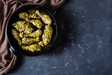 Canvas Print - Pesto Chicken in a black dish, flat lay