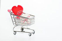 Selective Focus Present Box And Red Crochet Heart In Small Pink Shopping Cart ,on White Background With Small Red Hearts ,copy Space For Text, Shopping And Buying Present Valentine's Day Concept.