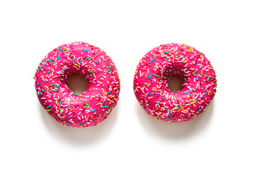 Two pink glazed doughnuts on a white background