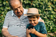 © Victor - Grandfather and grandson playing with a mobile phone