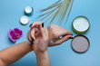 woman's hands apply cream each other on blue background with cosmetic products jars 