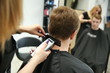 hairdresser's hands doing haircut to young man in a beauty salon