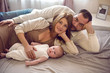© saulich84 - mom and dad are lying on the bed with the baby
