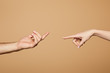 © LIGHTFIELD STUDIOS - cropped view of man and woman reaching each other with fingers isolated on beige