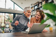 © bnenin - Senior mother and adult daughter relaxing and looking at laptop together, at home, portrait.