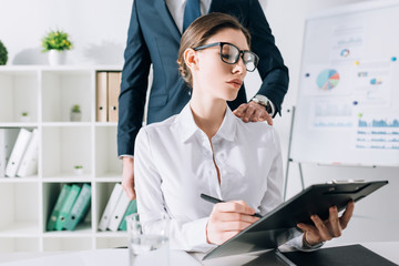 Wall Mural - cropped view of businessman touching attractive businesswoman in office