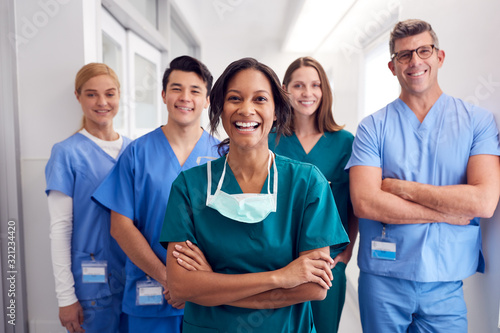 Fotomural Portrait Of Laughing Multi-Cultural Medical Team Standing In Hospital Corridor