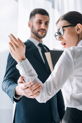 Wall Mural - selective focus of businessman touching hand of shocked secretary in office