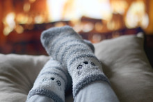 Feet In Cute Fuzzy Socks In Front Of A Fireplace. Selective Focus.