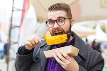 Handsome Man Eating Roasted Corn On The Street.
