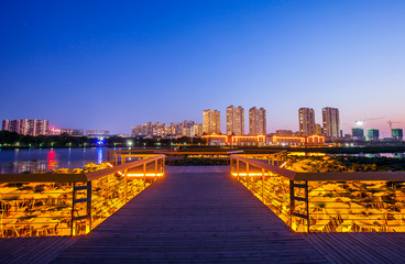 The wooden walkway by the river and the night view of the city